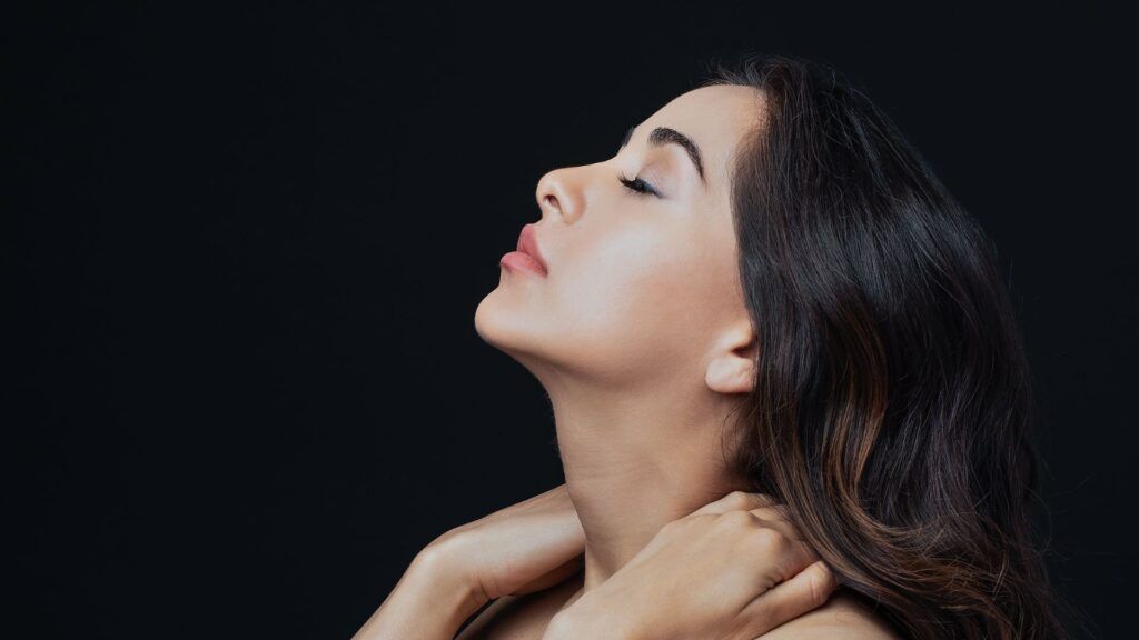 Revision Rhinoplasty of a woman looking up holding her neck